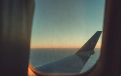 A photo of the wing of a plane mid-flight as you look through a porthole